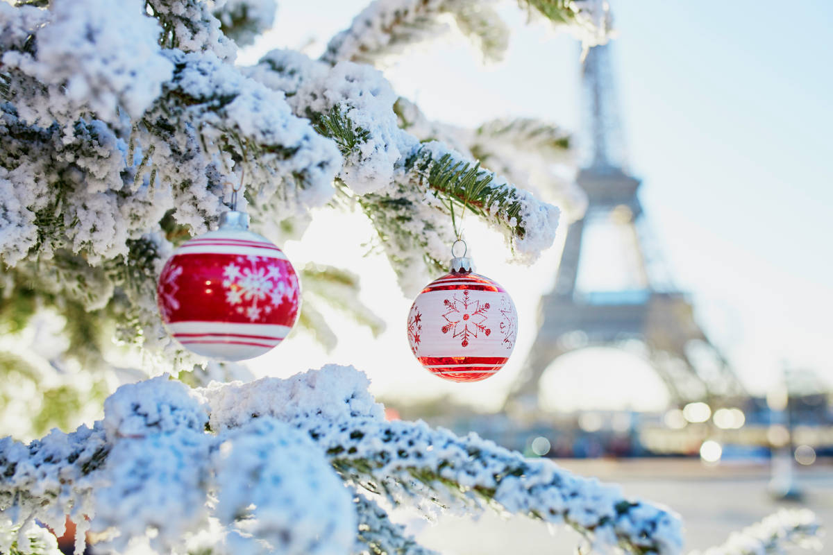 Einladungsanschreiben für Weihnachtsfeiern. Ob Sie in Paris oder München feiern, die ersten Hürde ist das Einladungsanschreiben. Das Bild zeigt einen festlich geschmückten und verschneiten Weihnachtsbaum. Im Hintergrund ist der Eifelturm zu sehen.