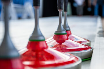 Eisstockschießen auf dem Tollwood Festival auf der Theresienwiese. Zu sehen sind vier rote Eisstöcke auf einer Kunsteisstockbahn