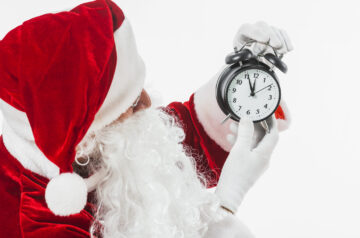 Weihnachtsmann der auf eine Uhr verweist
