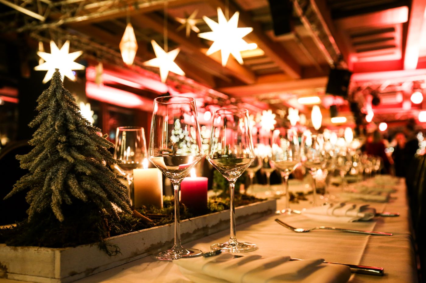 Das Bild zeigt einen festlich dekorierten Tisch in der Jochen Schweizer Arena. Als Deko dienen kleine Mini-Weihnachtsbäume und Kerzen sowie Zimtstangen und Tannenzweige. Die Serviette ist als Weihnachtbaum gefaltet.