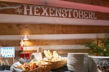 Weihnachtsfeiern-Geheimtipp 2025: Im festlich beleuchteten Hexenstüberl empfängt ein liebevoll angerichtetes Buffet die Gäste. Frische Focaccia, köstliche Snacks und warme Lichter schaffen eine Atmosphäre, in der Genuss und Gemütlichkeit perfekt zusammenfließen.