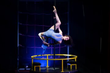Artistin zeigt eine elegante Akrobatik-Performance an der Pole auf einer beleuchteten Bühne.